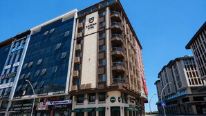A multi-story building with a KAGCAR HOTEL sign, a modern glass facade, and several ground-level shops. - Kaçkar Otel (Rize)