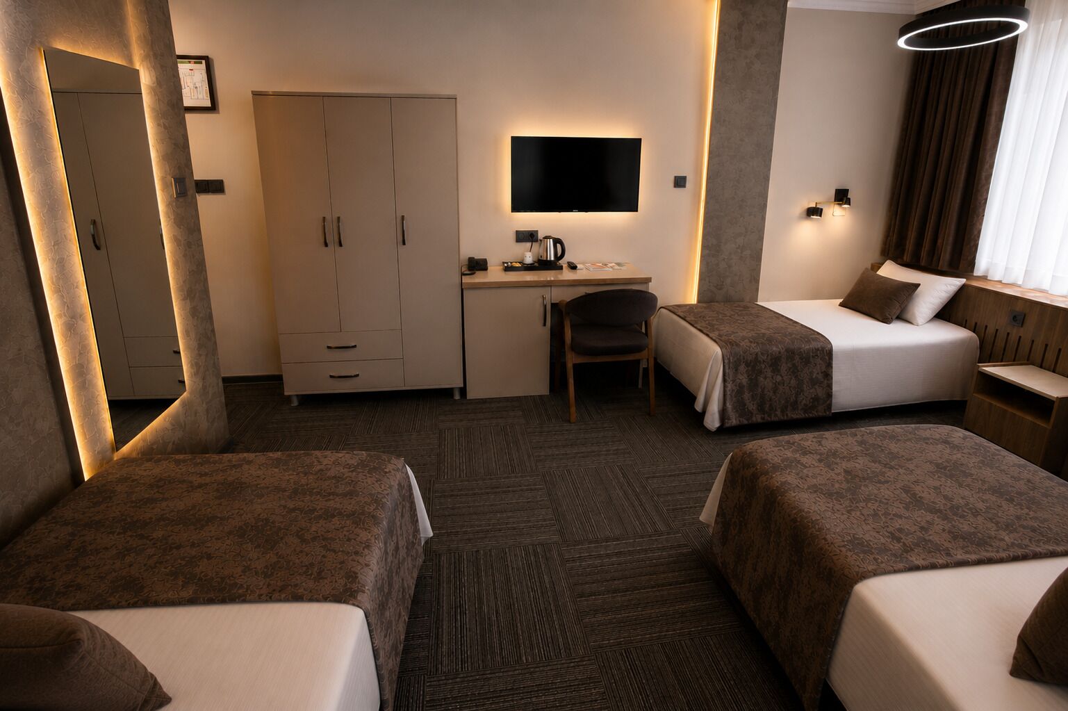 A hotel room with two beds, a desk, a chair, a television, and a wardrobe.