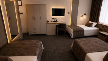 A hotel room with two beds, a desk, a chair, a television, and a wardrobe.