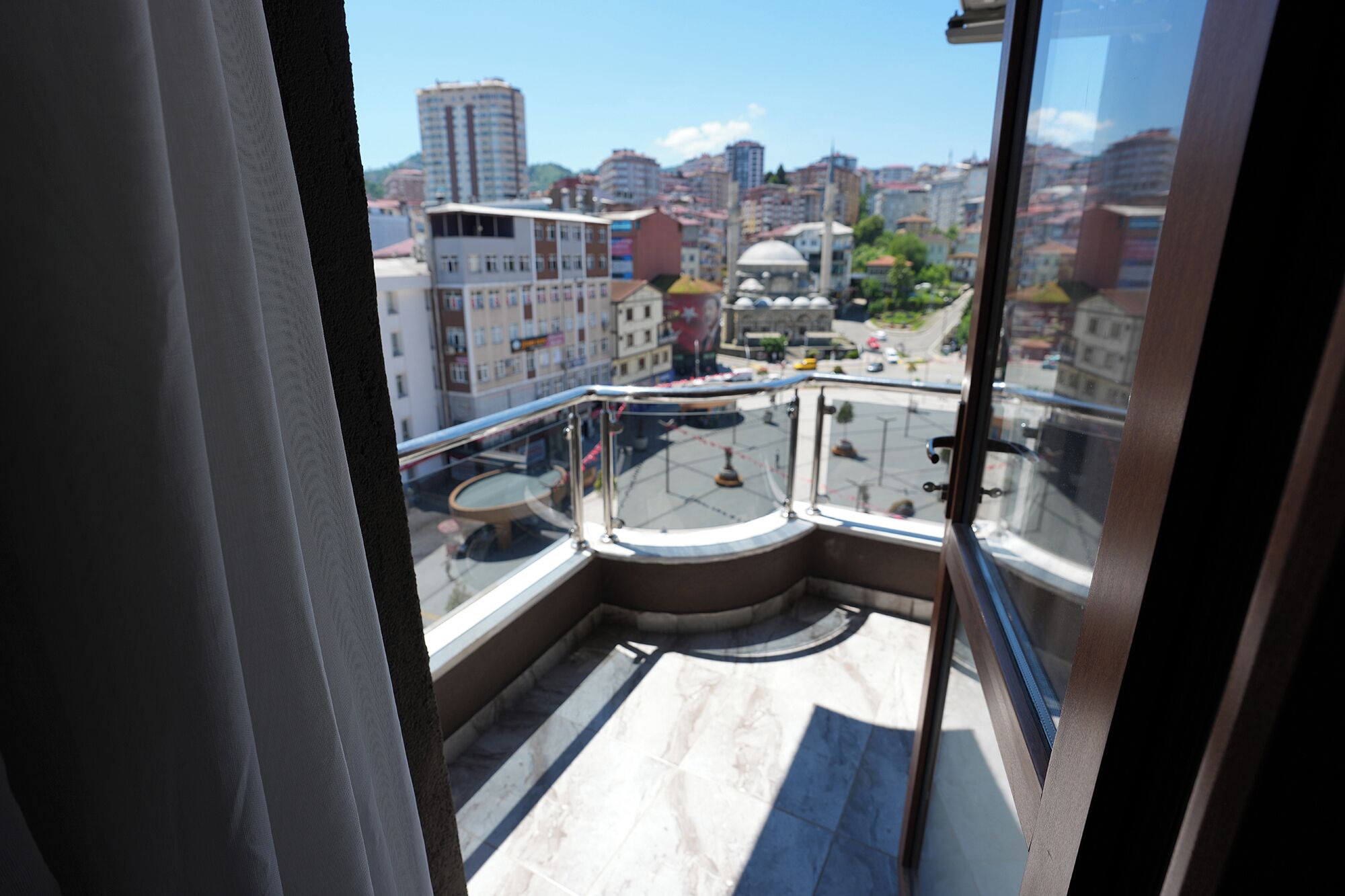 A balcony with a glass railing overlooking a cityscape with buildings and a dome structure.