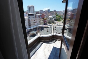 A balcony with a glass railing overlooking a cityscape with buildings and a dome structure.