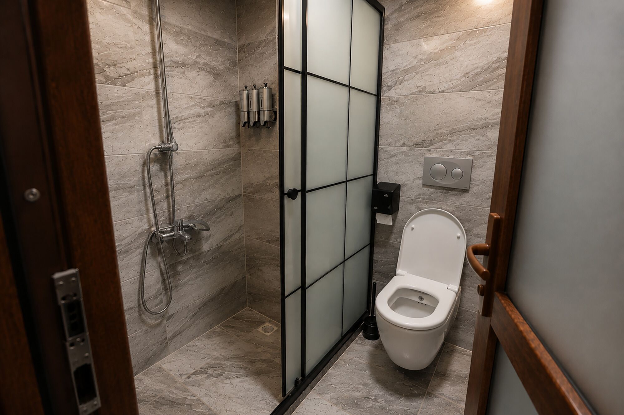 A bathroom with a shower, toilet, and a hand dryer.