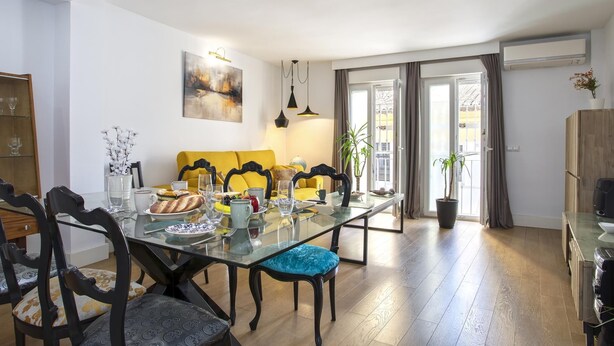 Un comedor con mesa de vidrio, sillas y sofá amarillo.