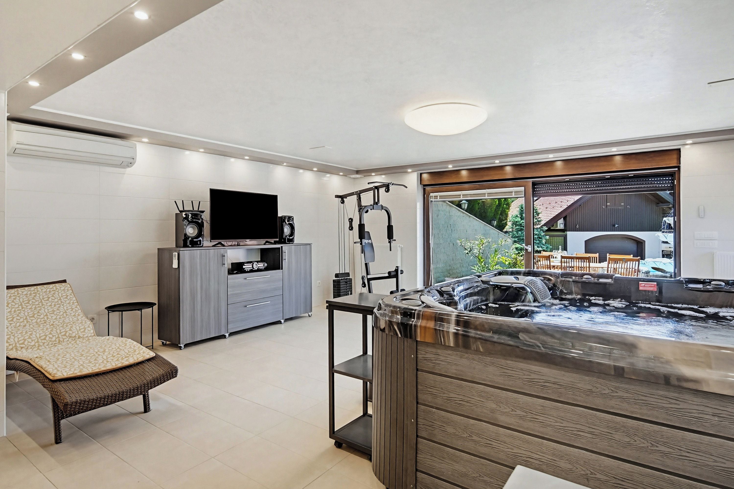 Un salon moderne comprenant un canapé, un téléviseur, un coin cuisine et un jacuzzi.