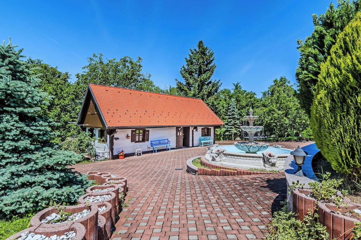 A building with a red-tiled roof, a fountain, and a paved walkway leading to it.