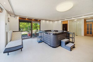 Ein moderner Innenraum mit Whirlpool, einer Sitzecke und Blick durch eine Glastür.