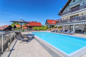A swimming pool with lounge chairs, a covered area with an umbrella, and a building with balconies. - Hillside Retreat With Pool & Wellness (Gornja Stubica)