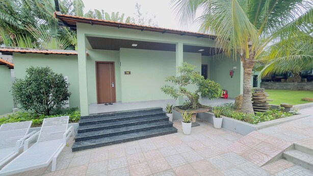 A building with a green facade, a brown door, and a staircase leading to the entrance.