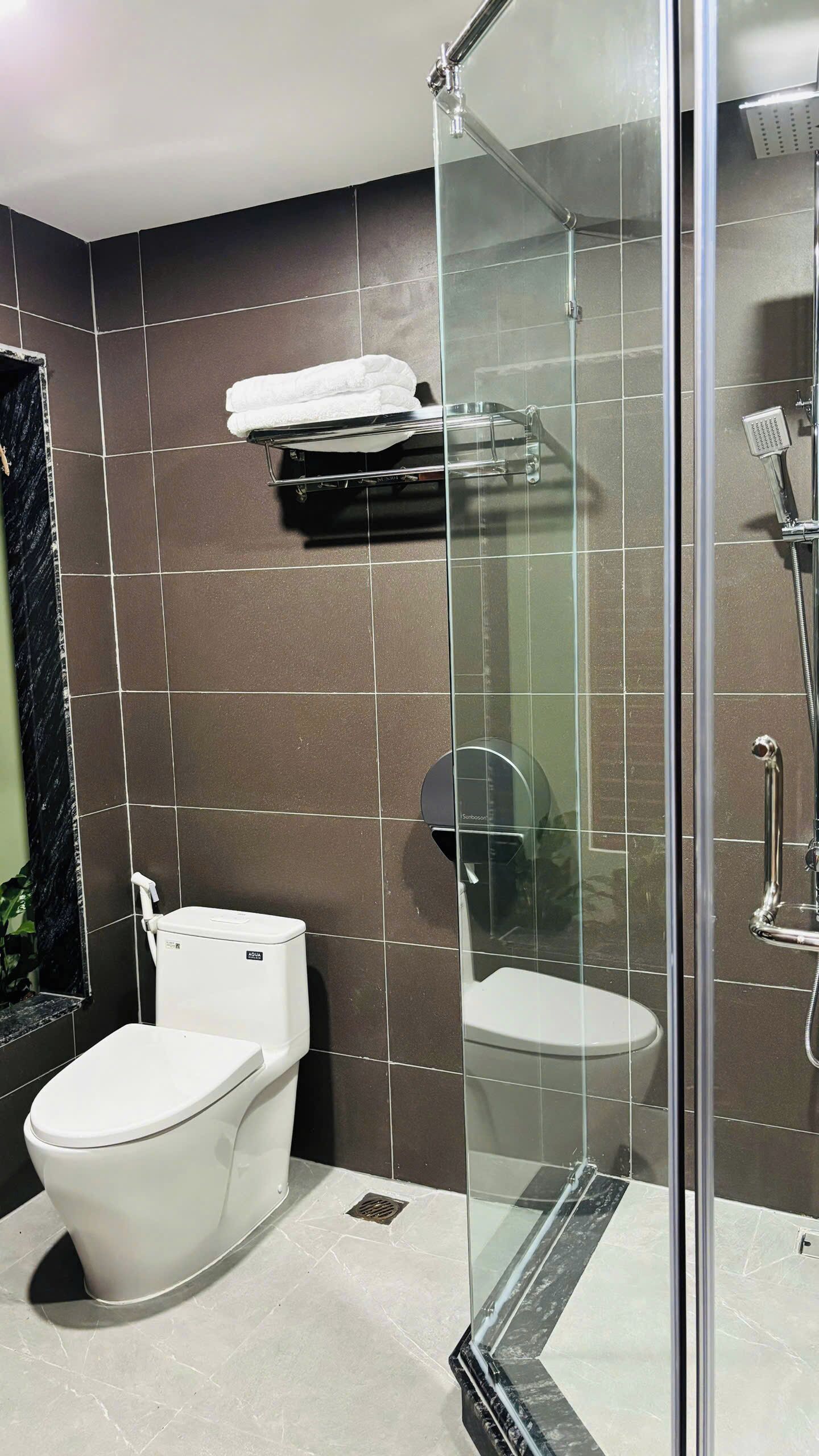 Un baño moderno con cabina de ducha de vidrio, inodoro y barra para toallas.