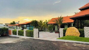 A hotel entrance with a paved walkway, stone pillars, and a large rock with 'Hawk House' inscribed. - Hannah Homestay Ho Tram  (Ho Chi Minh City)