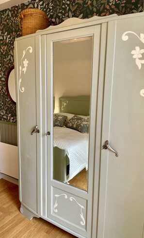 A wardrobe with a mirror, a bed with floral bedding, and a green patterned wallpaper. - AppartCosy 20 Country House Near “Régalante” (Landavran)