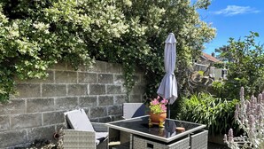Een terras met rieten meubilair, een tafel en een bloempot.