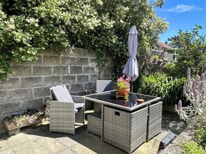 A patio with wicker furniture, a table, and a potted plant. - Pier View is a seafront property with amazing views and dramatic sunsets. (Pier View)