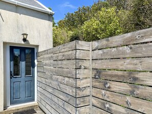 A house with a dark blue door, a light-colored exterior wall, and a wooden fence. - Pier View is a seafront property with amazing views and dramatic sunsets. (Pier View)