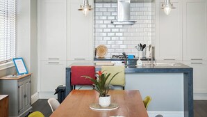 Een moderne keuken met witte kasten, een centraal eiland en hangende lampen.