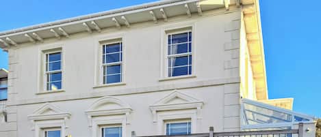 A white building with three windows and a balcony.