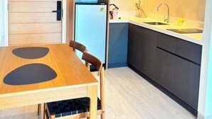 Een moderne keuken met houten kastjes, een ingebouwde magnetron, een spoelbak en een eethoek met een tafel en stoelen.