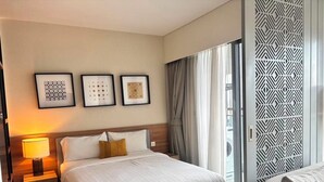Een hotelkamer met een groot bed, een nachtkastje met een lamp en drie kunstwerken in lijsten aan de muur.