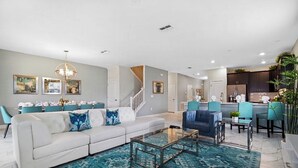 Una sala de estar moderna con un sofá blanco, una mesa de centro de vidrio y un tapete azul estampado.