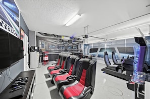 A futuristic control room with multiple screens, a central console, and a seating area with red and black seats. - Game Room + Theater + Pool + Hot Tub | 15-Min Disney | Luxury 8BR Disney Villa (Davenport)