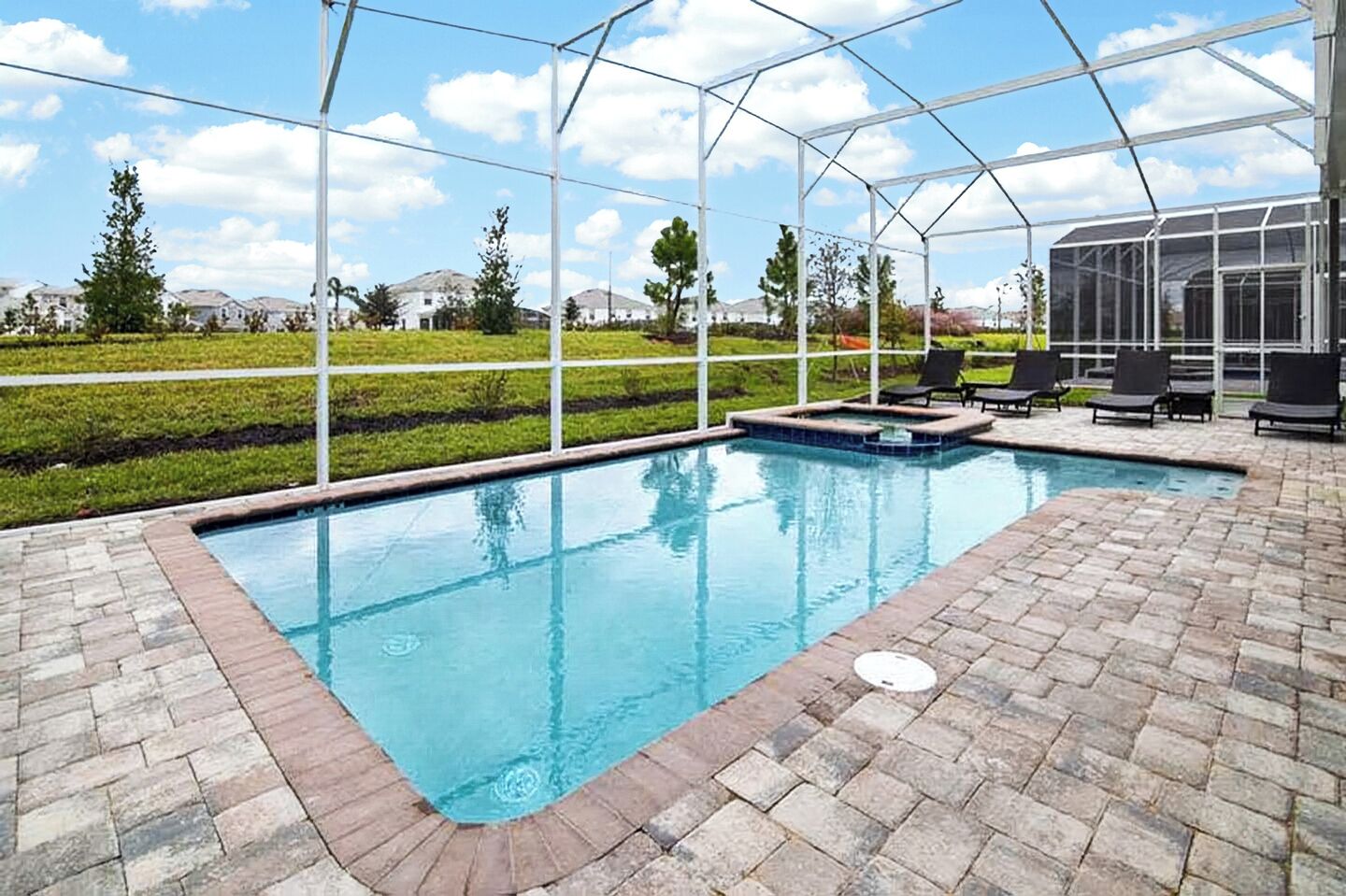 Enclosed private swimming pool and patio area under a bright, sunny sky.