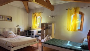 A bedroom with two beds, a desk, a wardrobe, and a window with yellow curtains.
