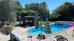 A backyard with a swimming pool, patio furniture, and a gazebo.