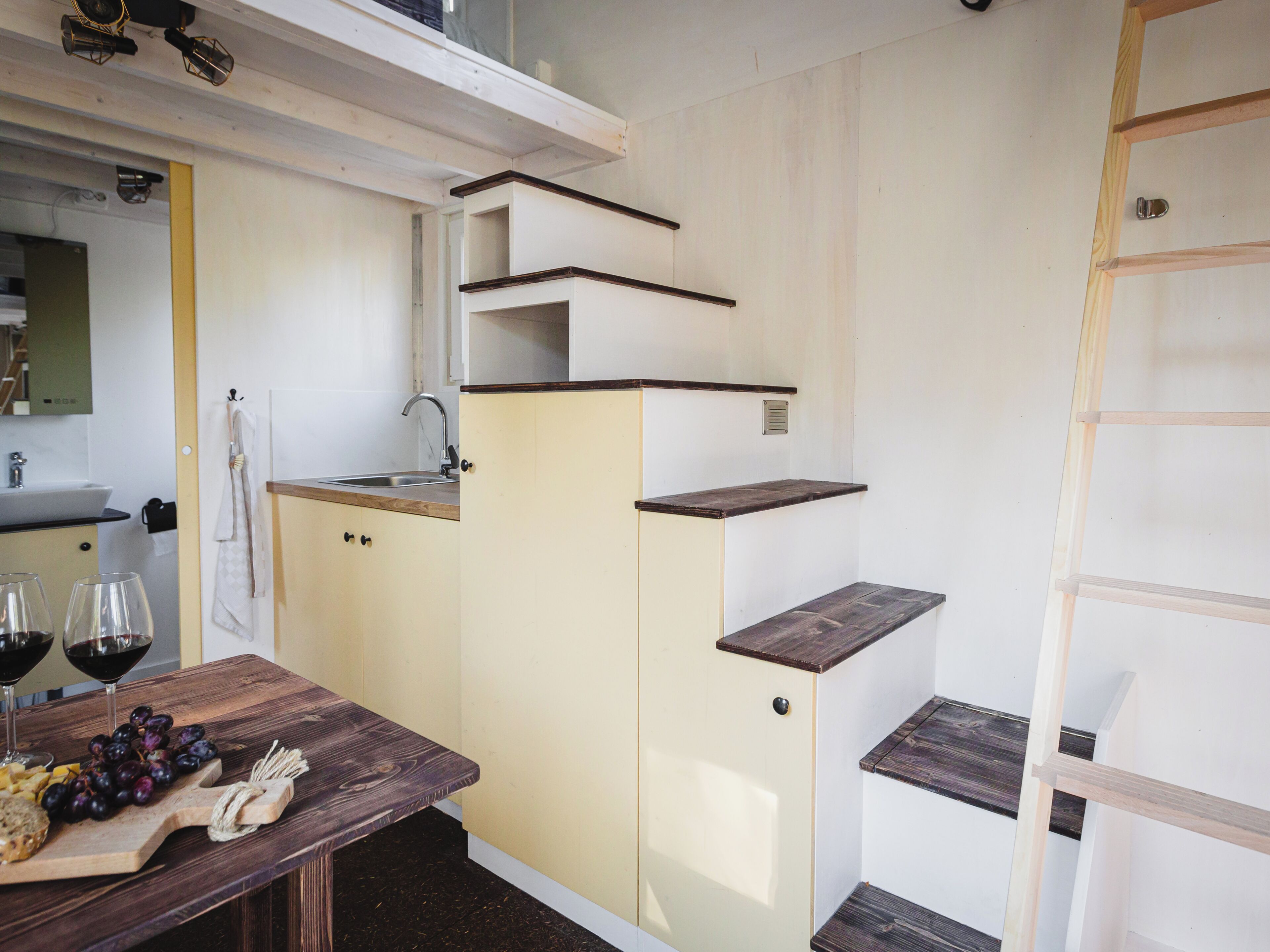 A compact kitchen with a sink, countertop, and wooden shelves.