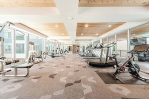 Et fitnesscenter med løbebånd, træningsmaskiner og store vinduer.
