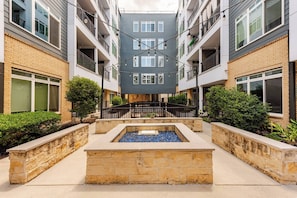 A multi-story residential building with balconies, a central courtyard with a water feature, and a stone pathway. - Riverwalk Downtown Luxury Pool & Free Parking (San Antonio)