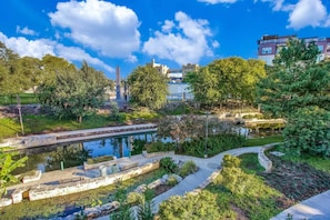 A landscaped garden with a pond, pathways, and trees. - Riverwalk Downtown Luxury Pool & Free Parking (San Antonio)