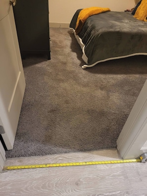 Ein Teppich ausgelegter Flur, der zu einem Schlafzimmer mit Bett und Kommode führt.