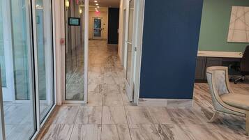 A hallway with glass doors, a blue accent wall, and a chair.