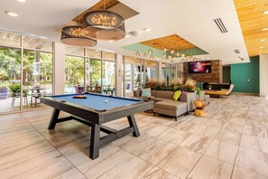 A pool table in a room with large windows, a sofa, and a TV.