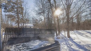 Ett bubbelbad utomhus, omgivet av snö, träd och ett staket i bakgrunden.