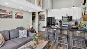 A modern kitchen with white cabinets, a central island, and stainless steel appliances. - Steps to Trails + Free Bus to Slopes | Balcony + Views | Serenity by the Slopes (Vail)