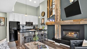A modern kitchen with a black refrigerator, white cabinets, and a built-in microwave. - Steps to Trails + Free Bus to Slopes | Balcony + Views | Serenity by the Slopes (Vail)
