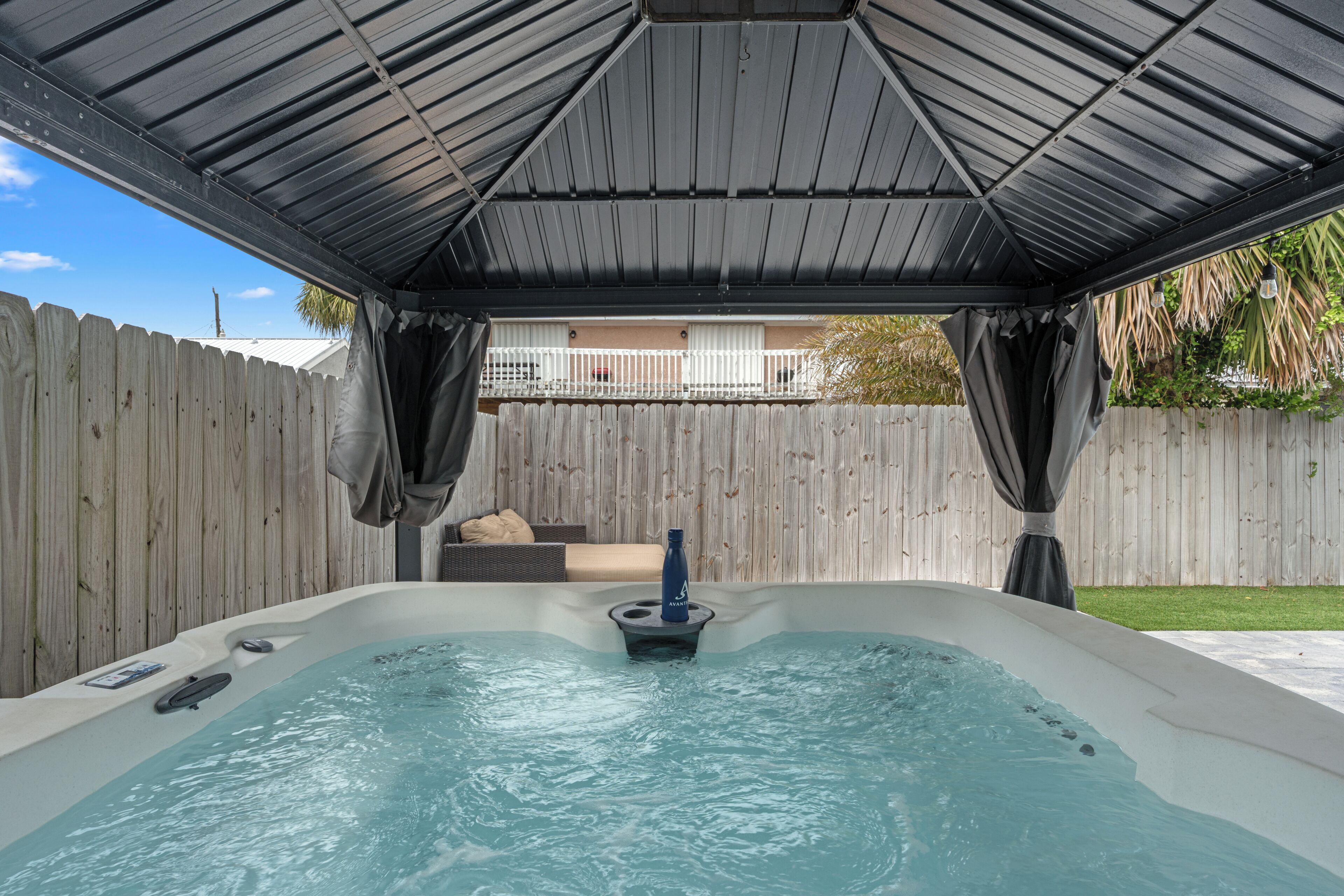 Un jacuzzi con techo metálico y valla de madera al fondo.