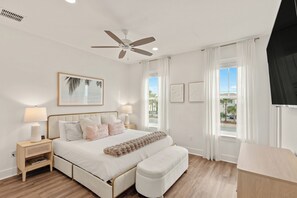 A bedroom with a bed, bedside tables, a ceiling fan, and a TV. - Walk to Beach • Shared Pool + Hot Tub • Near St. Andrews | Low Tide (Panama City Beach)