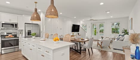 A modern kitchen with white cabinetry, stainless steel appliances, and a central island.
