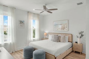 A bedroom with a bed, bedside tables, a ceiling fan, and a window with curtains. - Luxe Beach Retreat • Shared Pool + Hot Tub • Walk to Beach | High Tide (Panama City Beach)