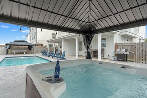 Ein Garten mit Whirlpool, Schwimmbad und Gartenmöbeln.