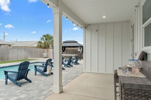 Ein überdachter Patio mit Pool, Sitzgelegenheit im Freien und Grillplatz.