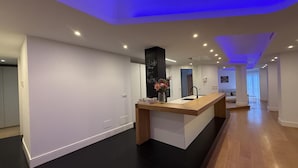 A modern kitchen with a central island, recessed lighting, and a black accent wall. - Oasis Urban Malaga in M Laga (Málaga)