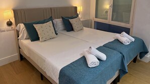 A double bed with two pillows, a blue bedspread, and two rolled towels. - Oasis Urban Malaga in M Laga (Málaga)