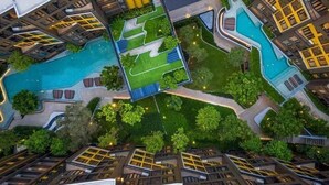 Vista aérea de un hotel moderno con varias construcciones, una piscina central y zonas ajardinadas.