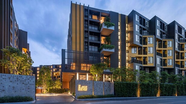 Un edificio moderno de varios pisos con balcones, una entrada con puerta y un letrero que dice 'The Base'.