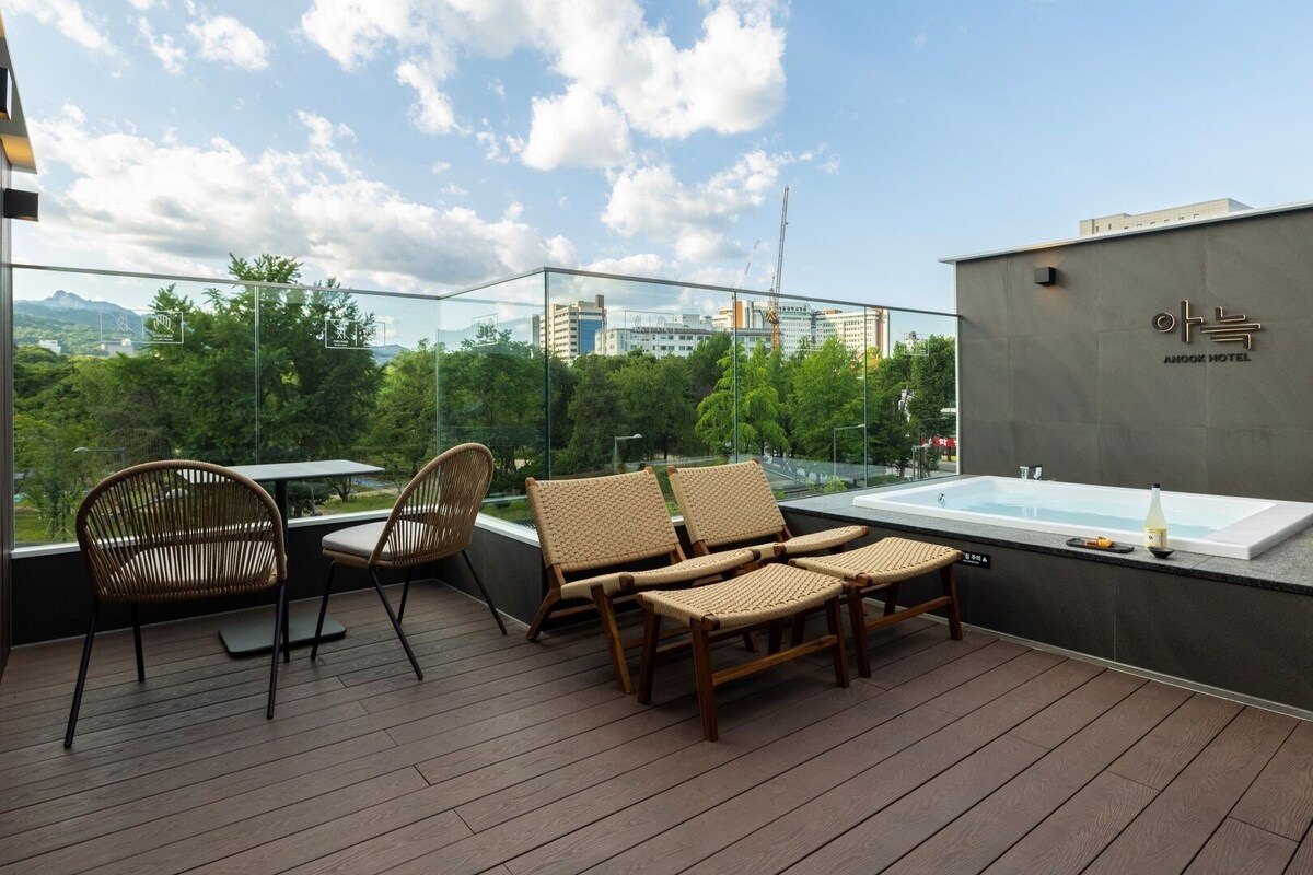 Una terraza en la azotea con un jacuzzi, sillas de mimbre y vistas a la ciudad.