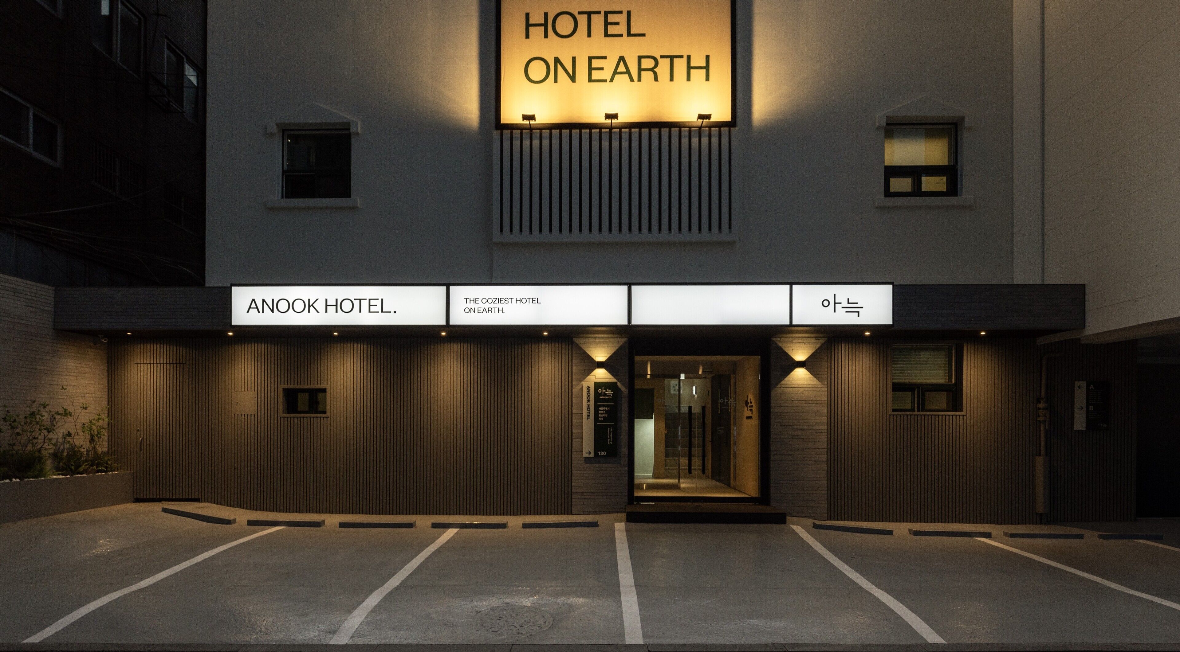 Entrada de un hotel con un cartel que dice 'HOTEL ONE EARTH' y 'ANOOK HOTEL'.