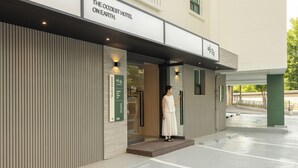 Entrada de un hotel con un cartel que dice 'THE COZIEST HOTEL ON EARTH'.